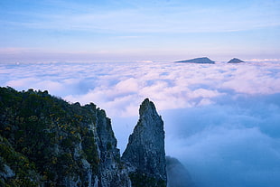 bird's eye view of rocky mountain cliff surrounded with sea clouds