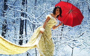 woman in sequin gold-colored floor gown holding red umbrella during winter daytime