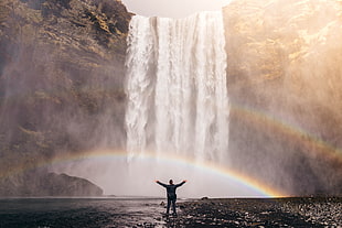 man standing on body of water seeing water fall