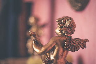 selective focus photography of cherub figurine playing stringed instrument