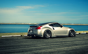 silver sports coupe near body of water under white cloud blue skies HD wallpaper