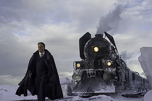 man wearing black coat near black train