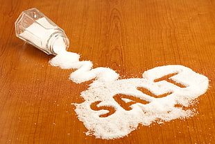 spilled salt on wooden surface from salt shaker