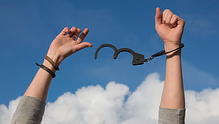 person raising her hands with handcuffs