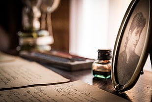papers on table near photo frame and vial HD wallpaper