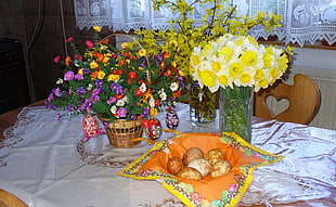 bouquet of flowers on vases and basket on white tablecloth