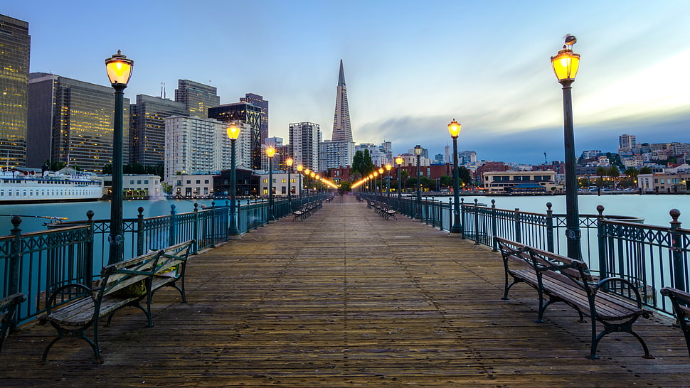 pathway bridge through city building with lamp post during daytime HD wallpaper