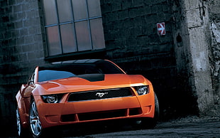 orange Ford Mustang parked near bricked building
