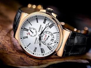 round gold-colored Ulysse Nardin chronograph watch with black leather strap