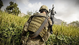 man wearing brown backpack holding rifle on green grass field HD wallpaper