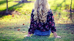 woman wears black and pink floral long-sleeved shirt sits on green grass