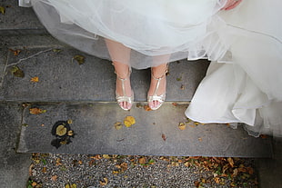 closeup photo of woman in white wedding gown standing on gray concrete floor