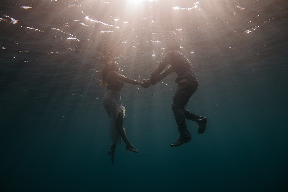 man and woman holding hands under body of water HD wallpaper