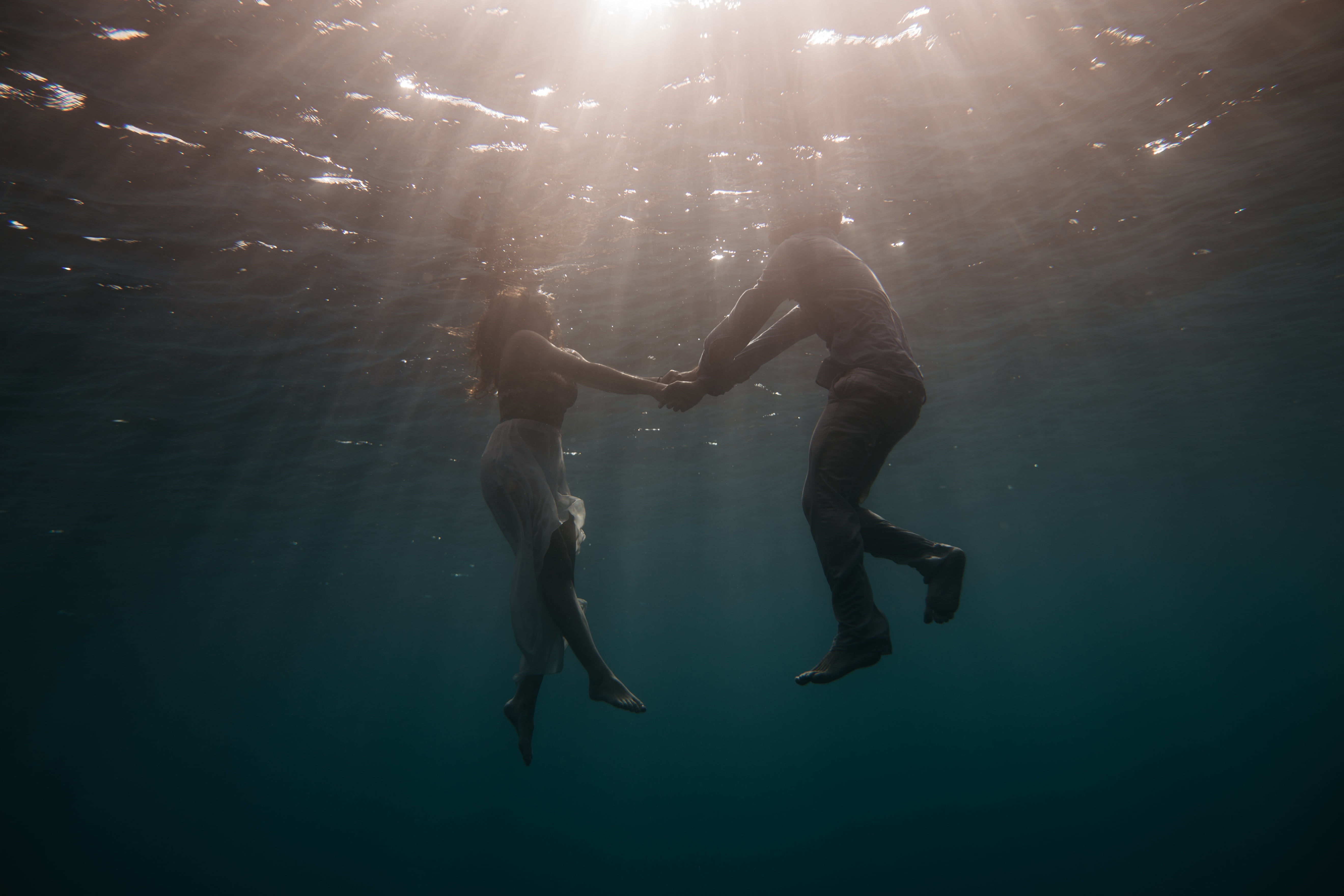 man and woman holding hands under body of water
