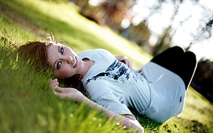 woman in white and black t-shirt lying on green grass field