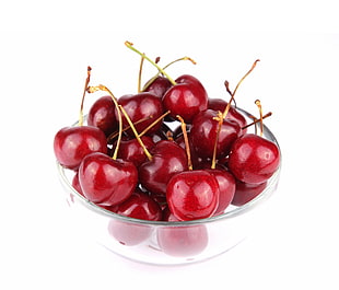 red unripe cherries in clear glass plate