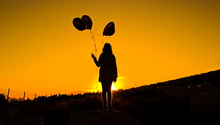 silhouette photo of woman holding balloon on top of mountain during golden hour HD wallpaper