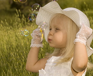 girl wearing sun hat blowing bubbles