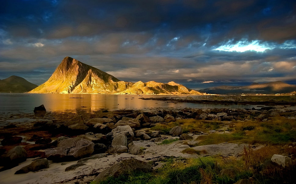 brown rocky mountain under black cloudy sky HD wallpaper