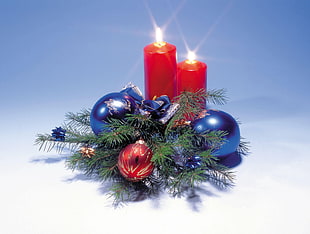 two red pillar candles with baubles