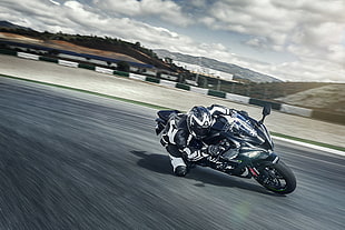person riding black sports bike speeding on track under cloudy sky during daytime HD wallpaper