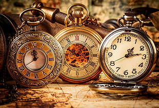 three gold-colored pocket watches displaying 12:00, 11:05, and 1:13 HD wallpaper