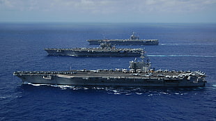 three gray aircraft carriers sailing during day