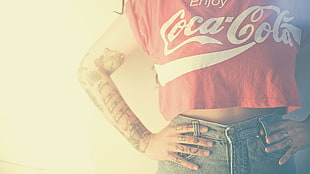 person wearing blue denim bottoms and Coca-Cola tops