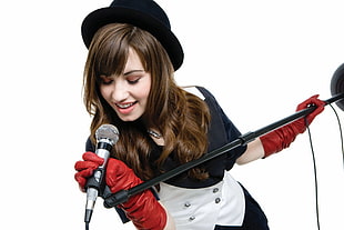 woman wearing pair of red gloves holding black microphones stand