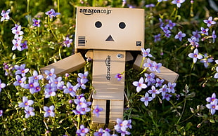 Amazon cardboard box robot design laying on purple petaled flowers