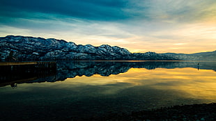 landscape photography of lake beside snow mountain during golden hour
