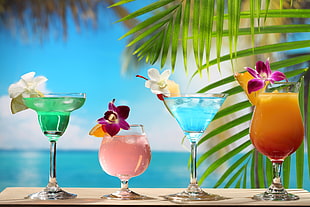 green margarita, pink cocktail, blue martini and yellow and red mixed drinks on beige surface