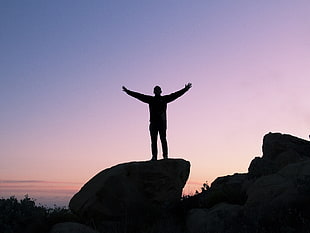 silhouette of person standing on rock HD wallpaper