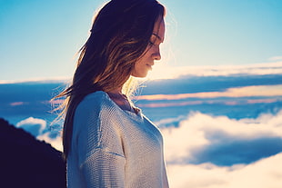 woman in white knit top next to white clouds during daytime