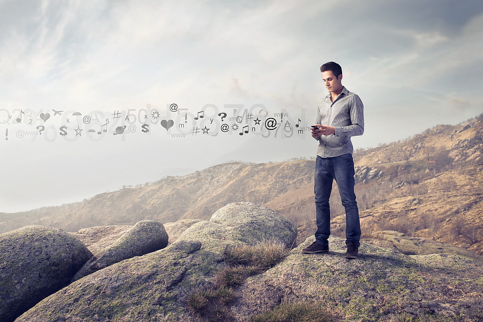 man holding smartphone standing on mountain HD wallpaper