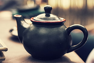 black ceramic tea pot placed on brown wooden panel