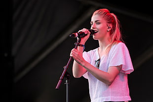 woman in white shirt holding a black microphone with black microphone stand