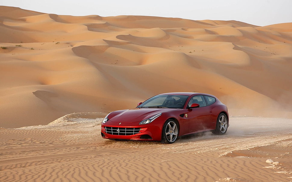 red Ferrari on desert during daytime HD wallpaper