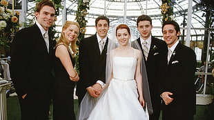 four men with one bridesmaid and bride taking a picture on the hall way