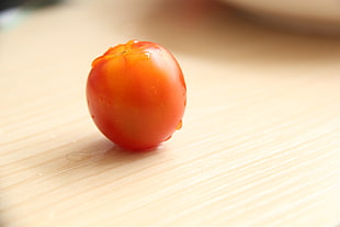 red tomato on brown wooden surface