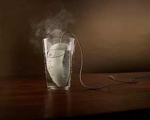 white corded computer mouse on clear glass cup