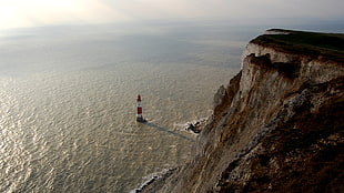 white and red lighthouse on body of water HD wallpaper