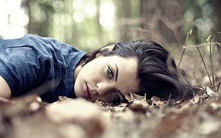 woman open eyes lying on dried leaves during daytime photo