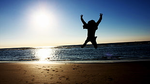 silhouette of man hopping on seashore