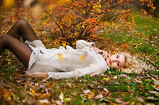 shallow focus photography of woman in gray sweater lying on green grass during daytime