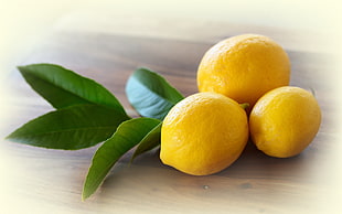 three lemon fruits on brown surface HD wallpaper