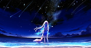 girl standing on beach under meteor shower on sky