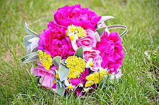 pink and yellow flowers bouquet placed on green grasses