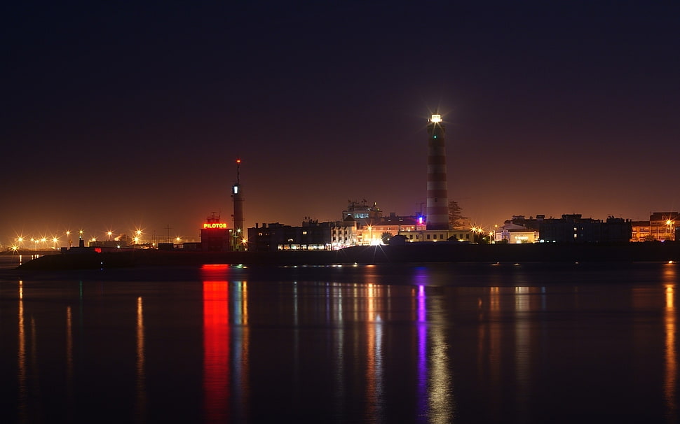 white and red striped lighthouse at nighttime HD wallpaper