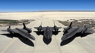 aerial shot of three black jets on runway